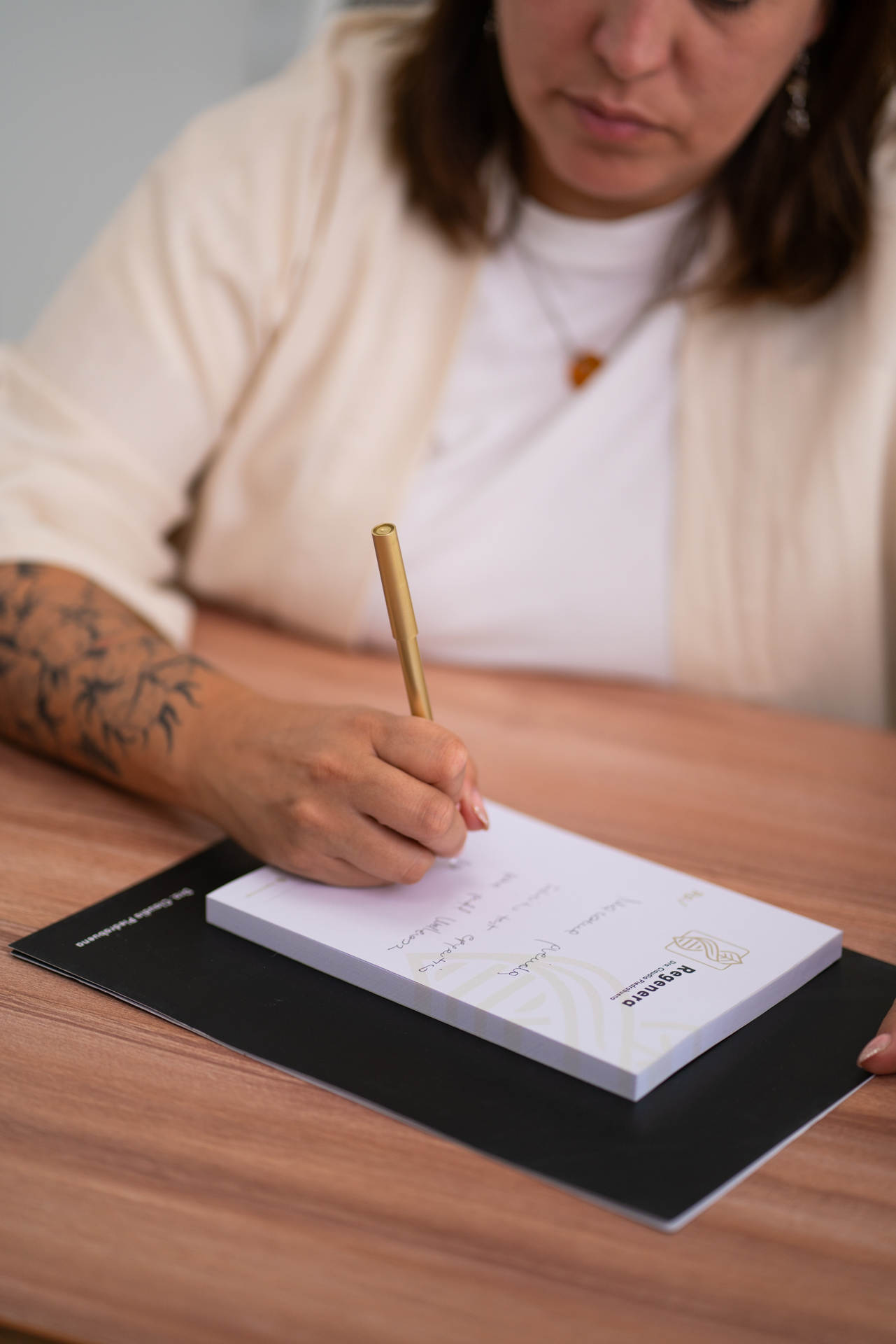 Claudia escribiendo en el cuaderno de Regenera con bolígrafo dorado